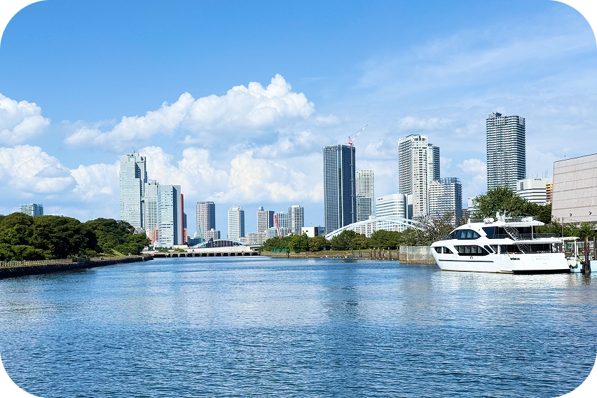 青空の下、高層ビル群を背景に流れる広い運河の風景