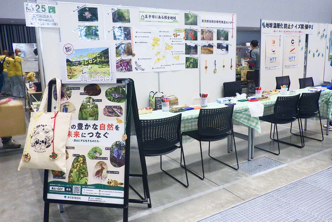 「東京の豊かな自然を未来につなぐ」というポスターや、八王子市の保全地域の地図が展示されたイベントブース