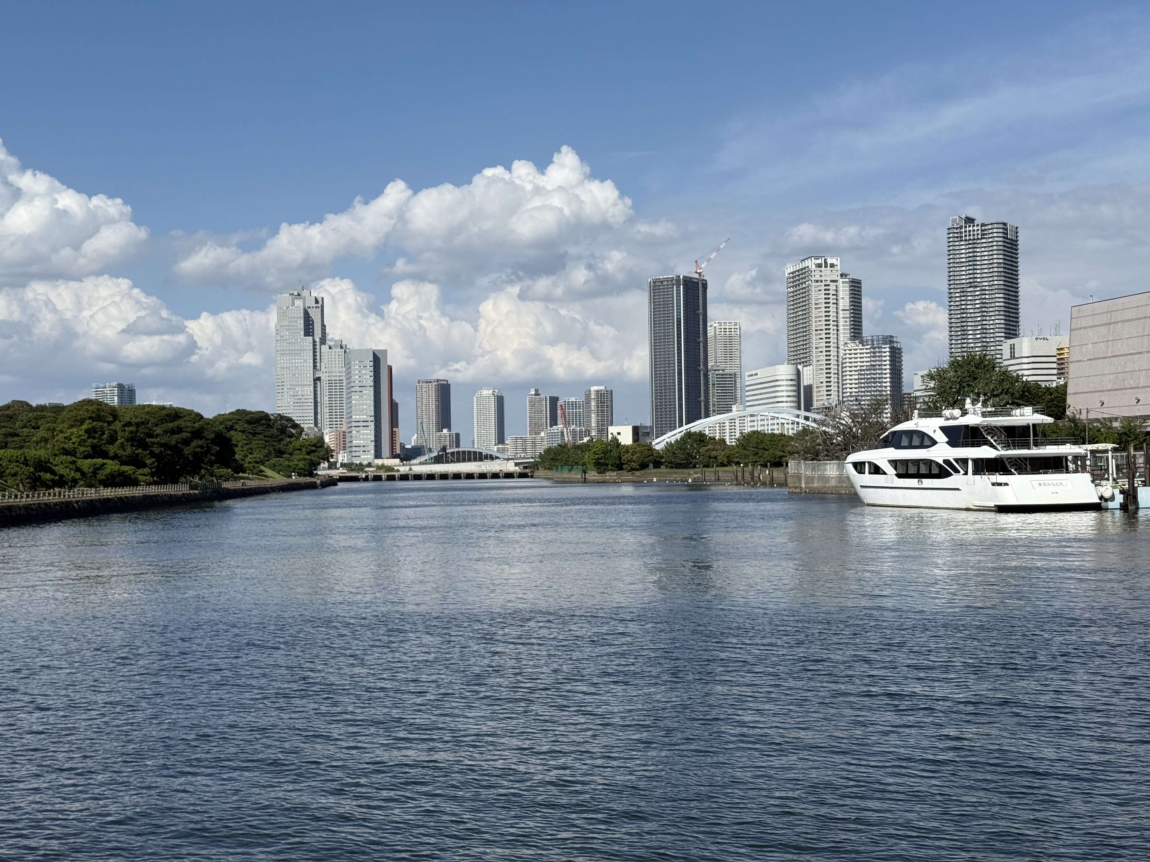 青空の下、高層ビル群を背景に流れる広い運河の風景