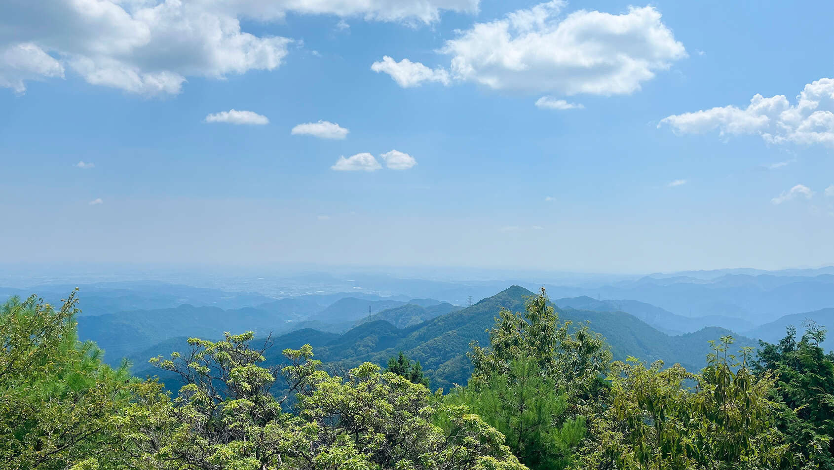 晴れた青空の下、遠くまで層をなして連なる山々のパノラマ風景