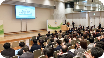 「第1回 Tokyo-NbS アクションアワード」の会場風景。前方のスクリーンにイベント名が表示され、多くの観客が座席からステージを見守っている様子。